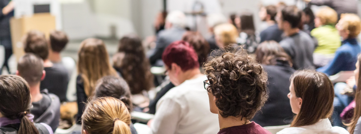 A group of people sit listening to a presentation.